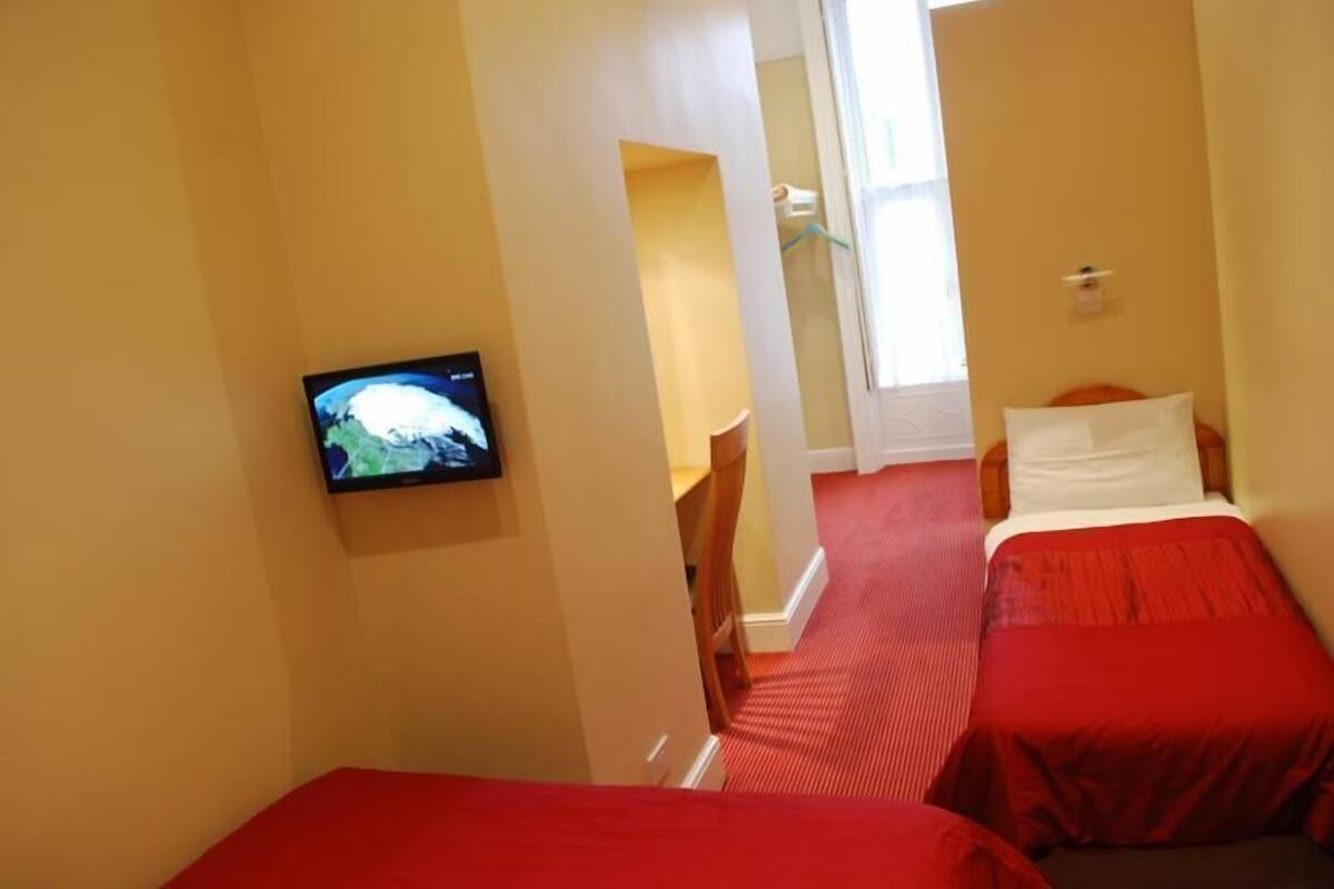 Ein Hotelzimmer mit zwei Betten, einem Fernseher und einem Fenster.