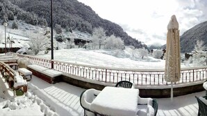 Un'area esterna innevata con un monumento in pietra, sedute e un edificio sullo sfondo.