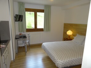 A bedroom with a bed, a desk, a chair, a TV, and a window with curtains. - Aparthotel Sant Andreu (Arinsal)
