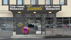 Un restaurante hotelero Club con fachada de piedra, amplias ventanas y una maceta con flores en el exterior.