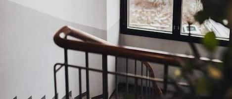A staircase with a metal handrail leading to a window with multiple panes.