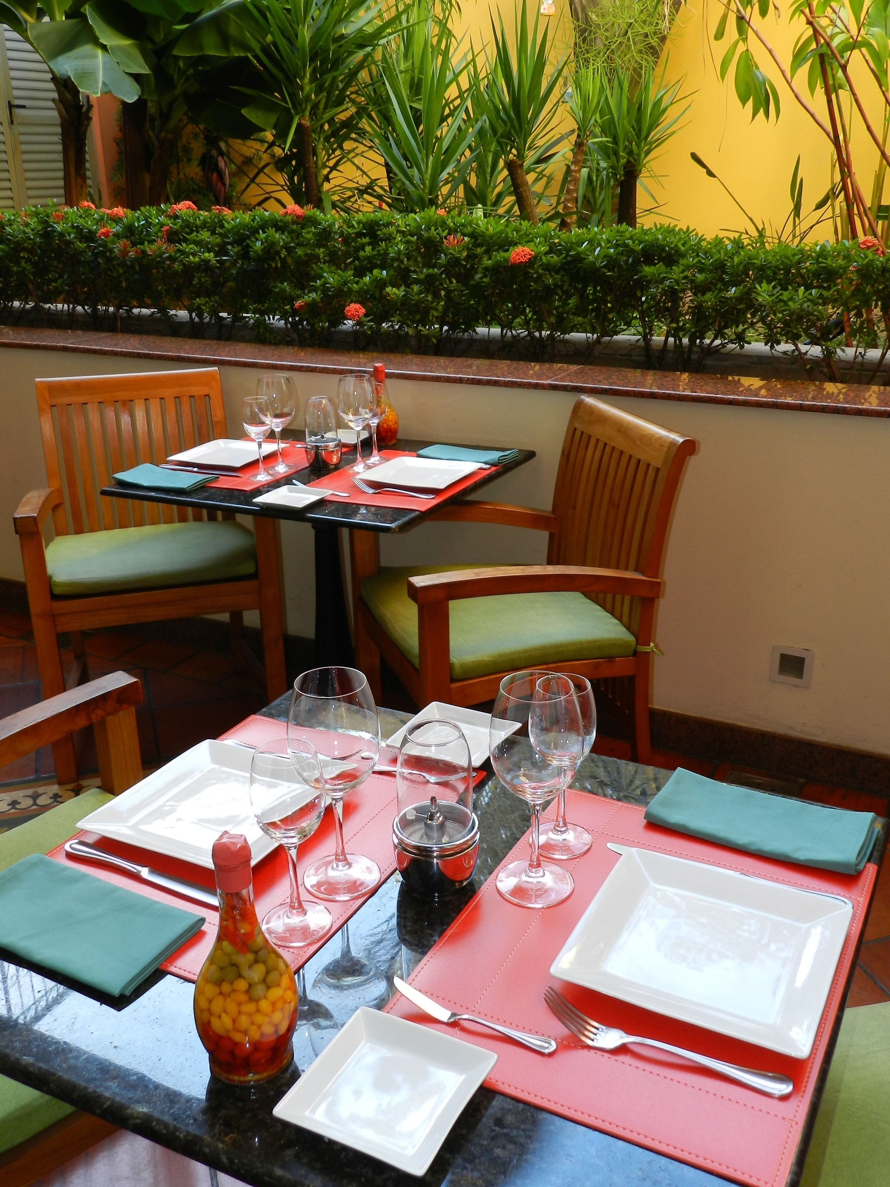 Una mesa dispuesta para dos, con botellas de salsas, copas de vino y platos.