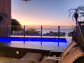 Una piscina al aire libre, sombrillas, sillones reclinables de piscina