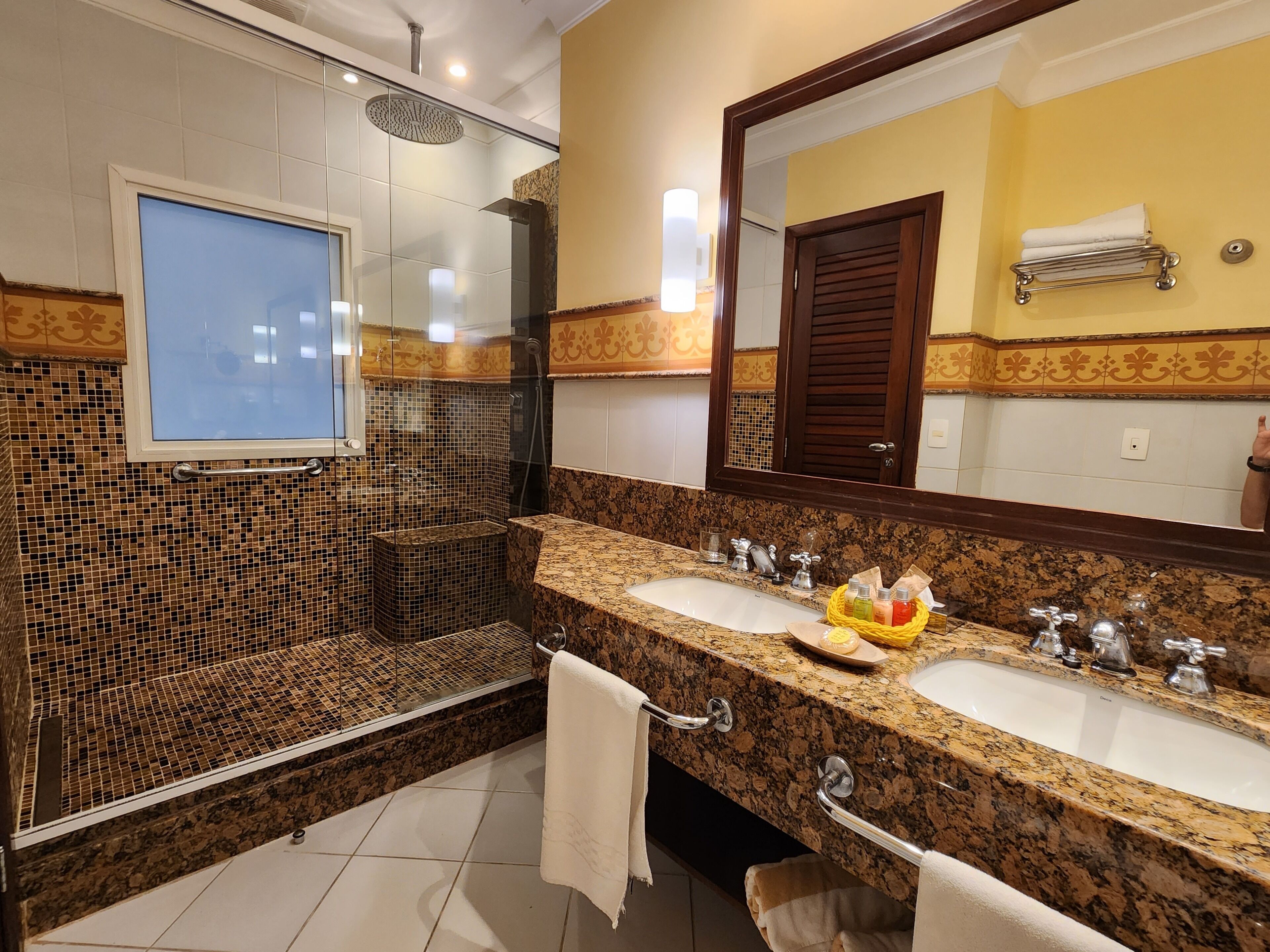 Baño con dos lavamanos, ducha y un espejo grande.