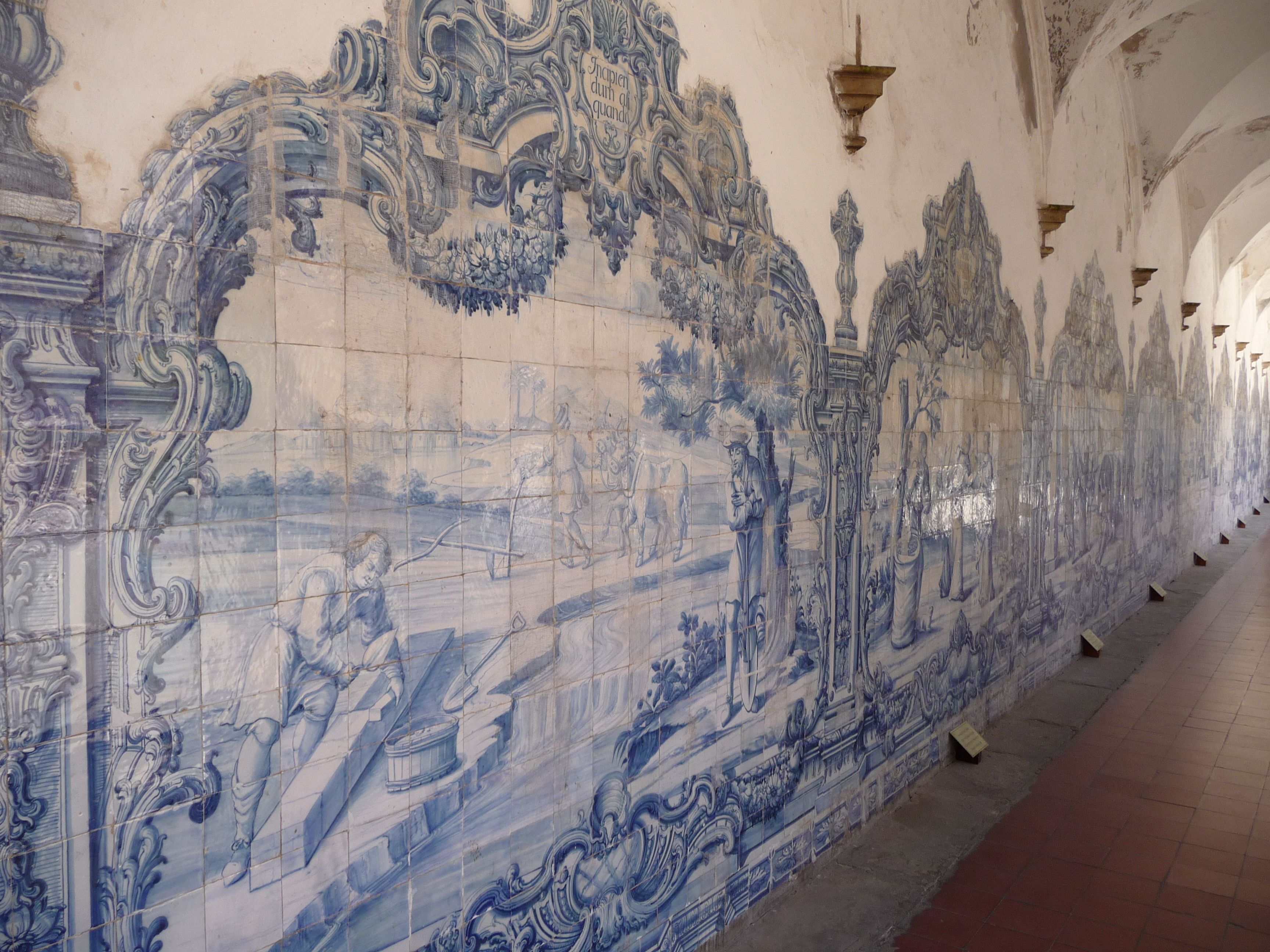 A corridor with a long, ornate tiled wall featuring intricate blue designs and architectural details.