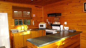 Cocina de cabaña de madera con refrigerador, microondas, estufa, pileta y una isla grande.
