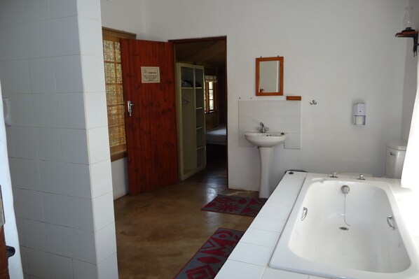 A bathroom with a bathtub, sink, and wooden door.