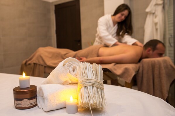 A massage table with towels, candles, and a bundle of twigs.