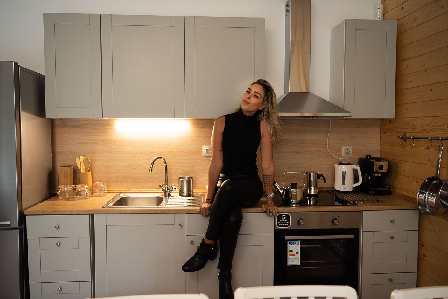 A modern kitchen with a stainless steel sink, a coffee machine, and wooden cabinets.