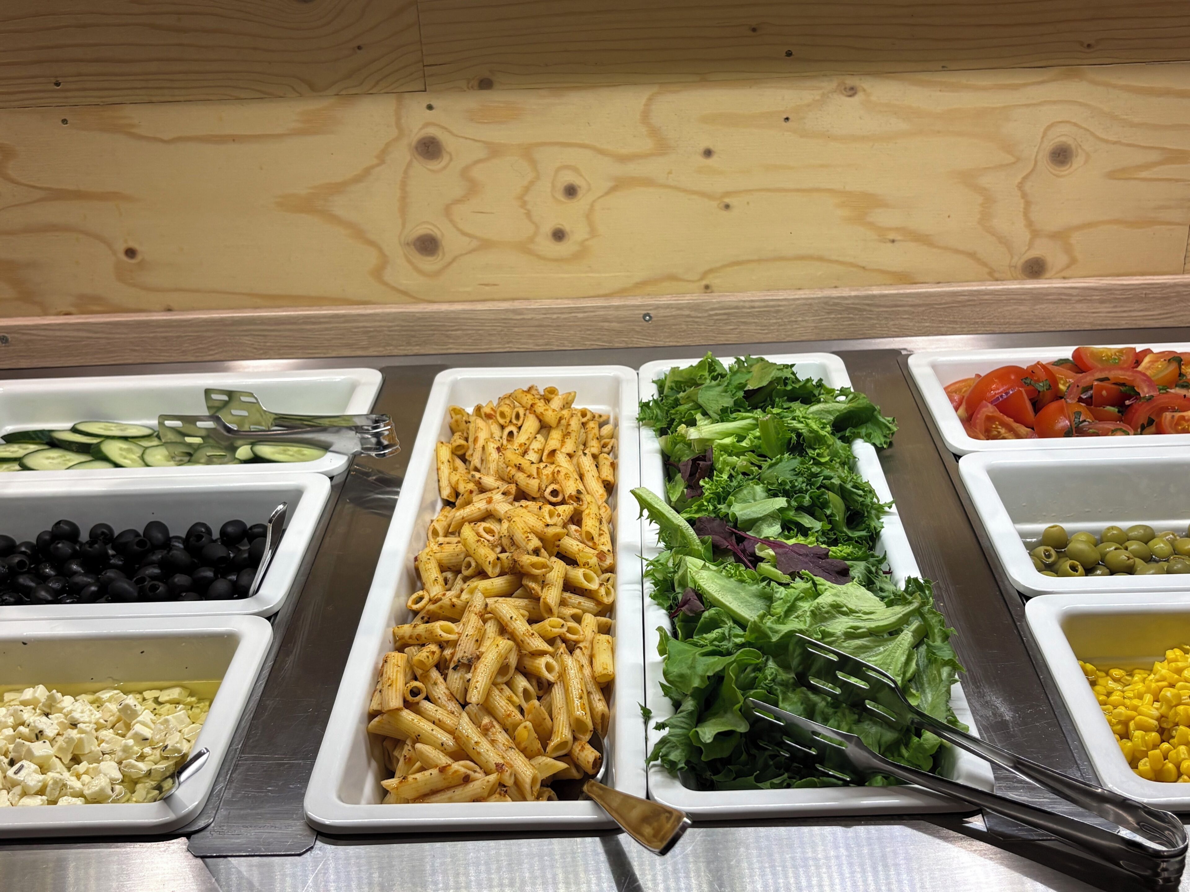Un bufé con diversas opciones de comida, como pasta, ensaladas y verduras.