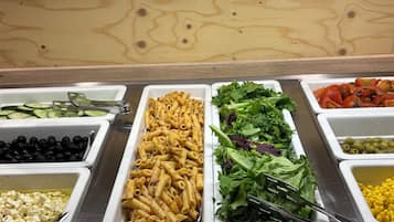 Un bufé con diversas opciones de comida, como pasta, ensaladas y verduras.