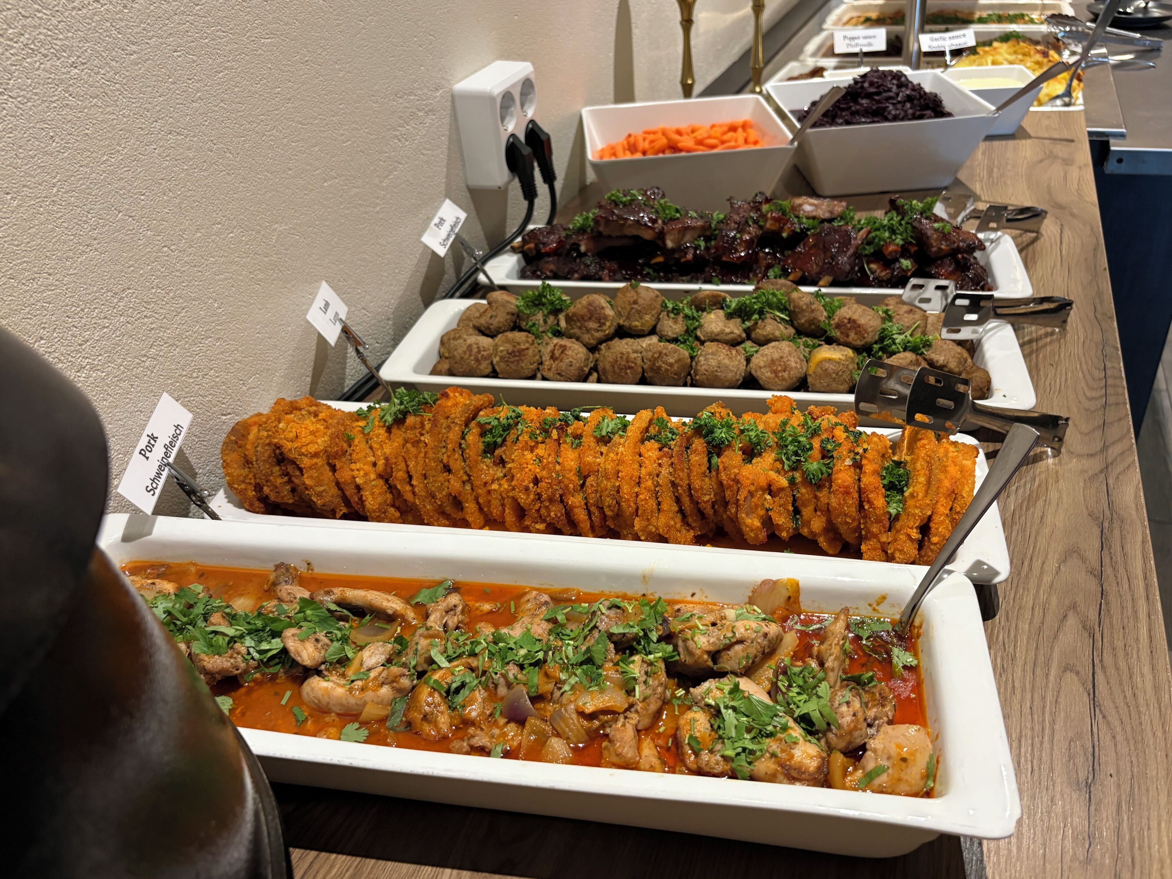 Buffet com diversos pratos, incluindo almôndegas, um prato de carne e um prato de frango.