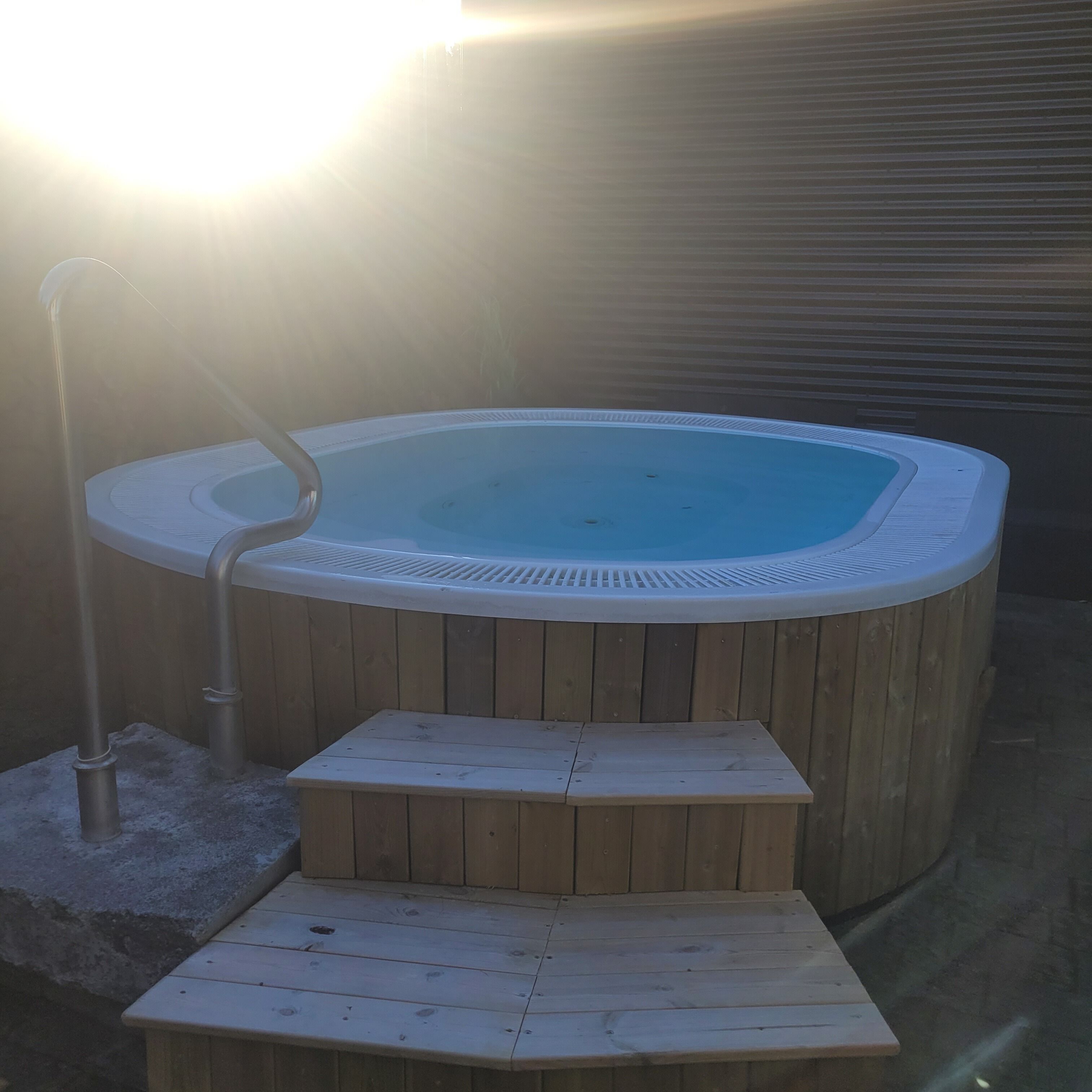 Un jacuzzi con cubierta de madera y escalones de acceso.