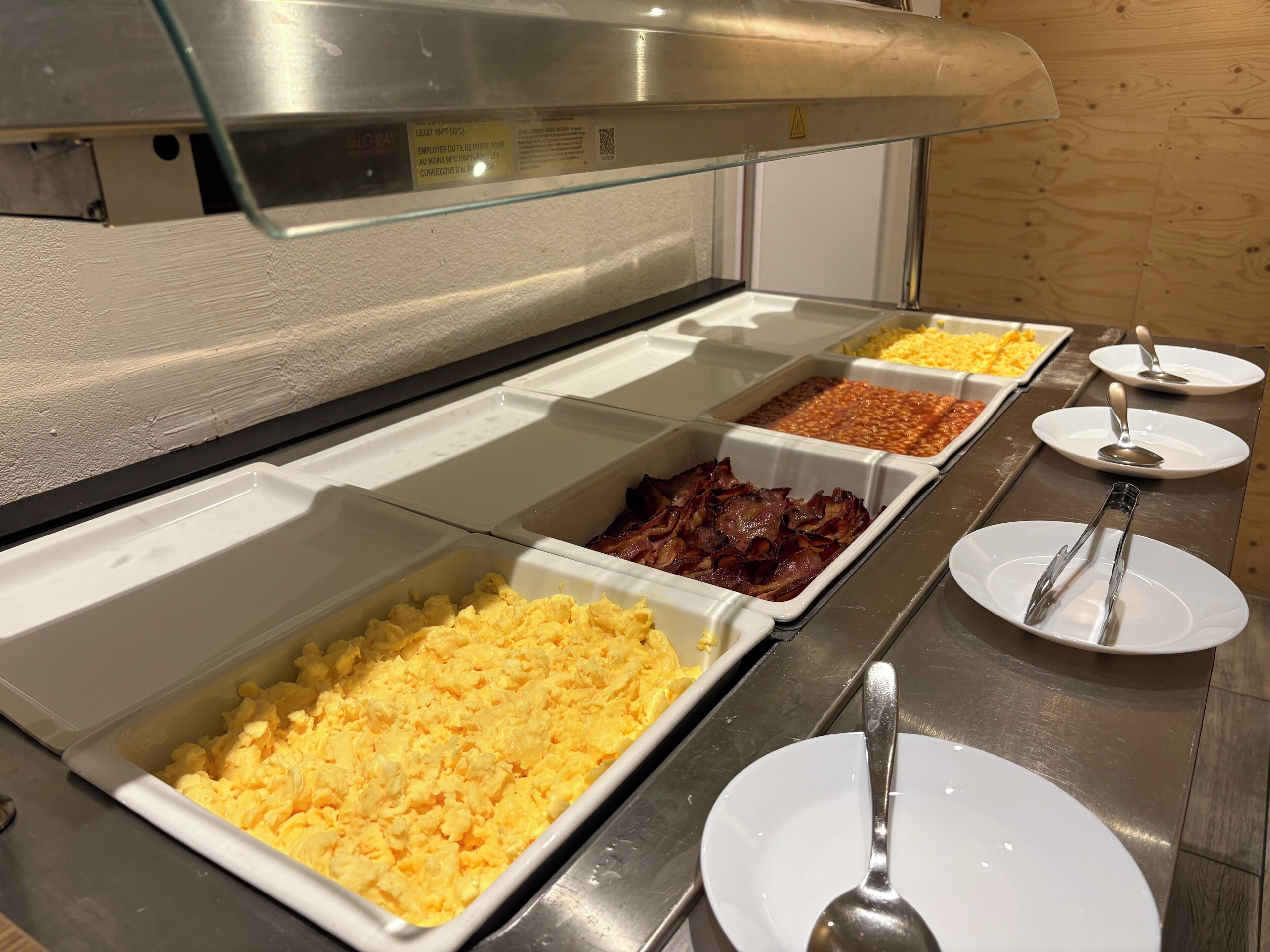 A buffet with various food options including scrambled eggs, bacon, and baked beans.
