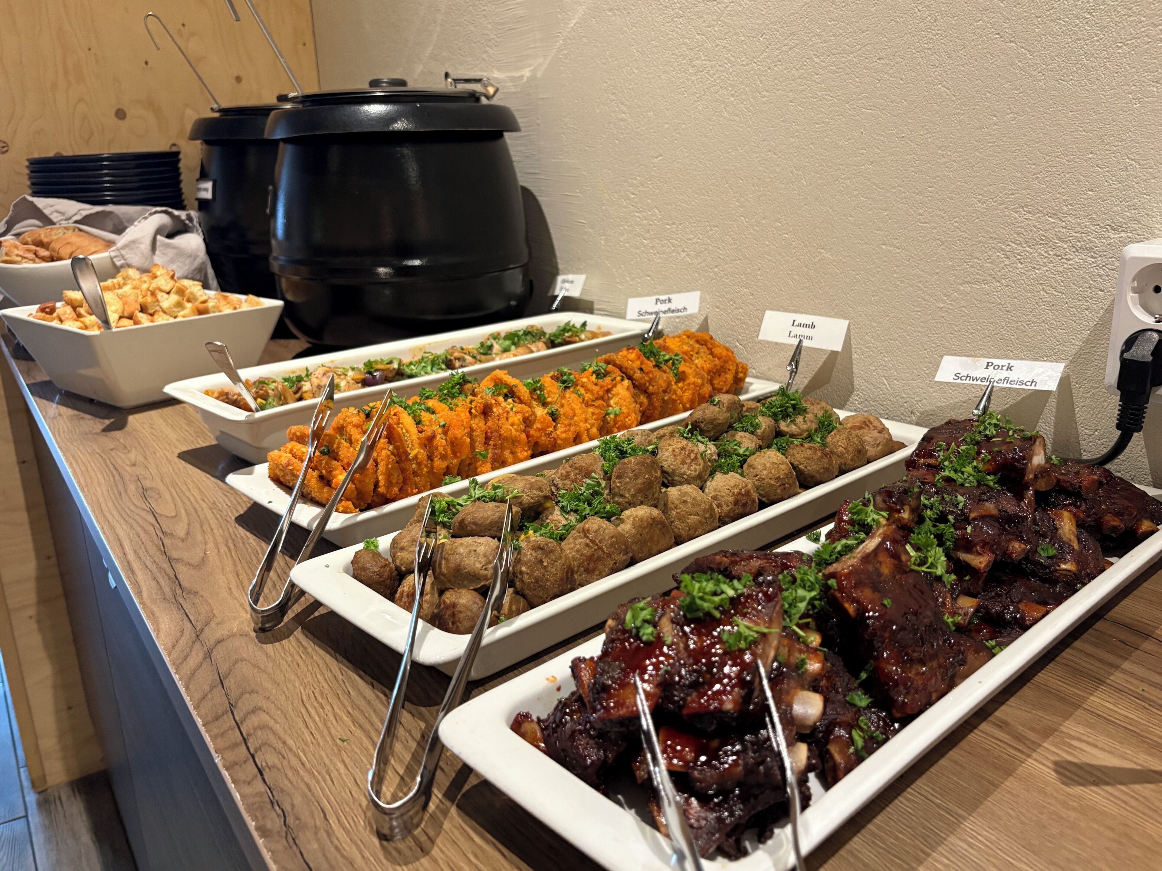 A buffet with various dishes including meatballs, fried chicken, and ribs.