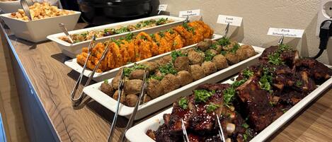 A buffet with various dishes including meatballs, fried chicken, and ribs.