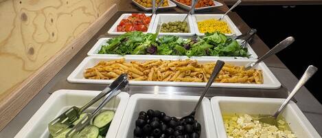 Un buffet proposant une variété de plats, notamment des pâtes, des salades et d’autres mets.