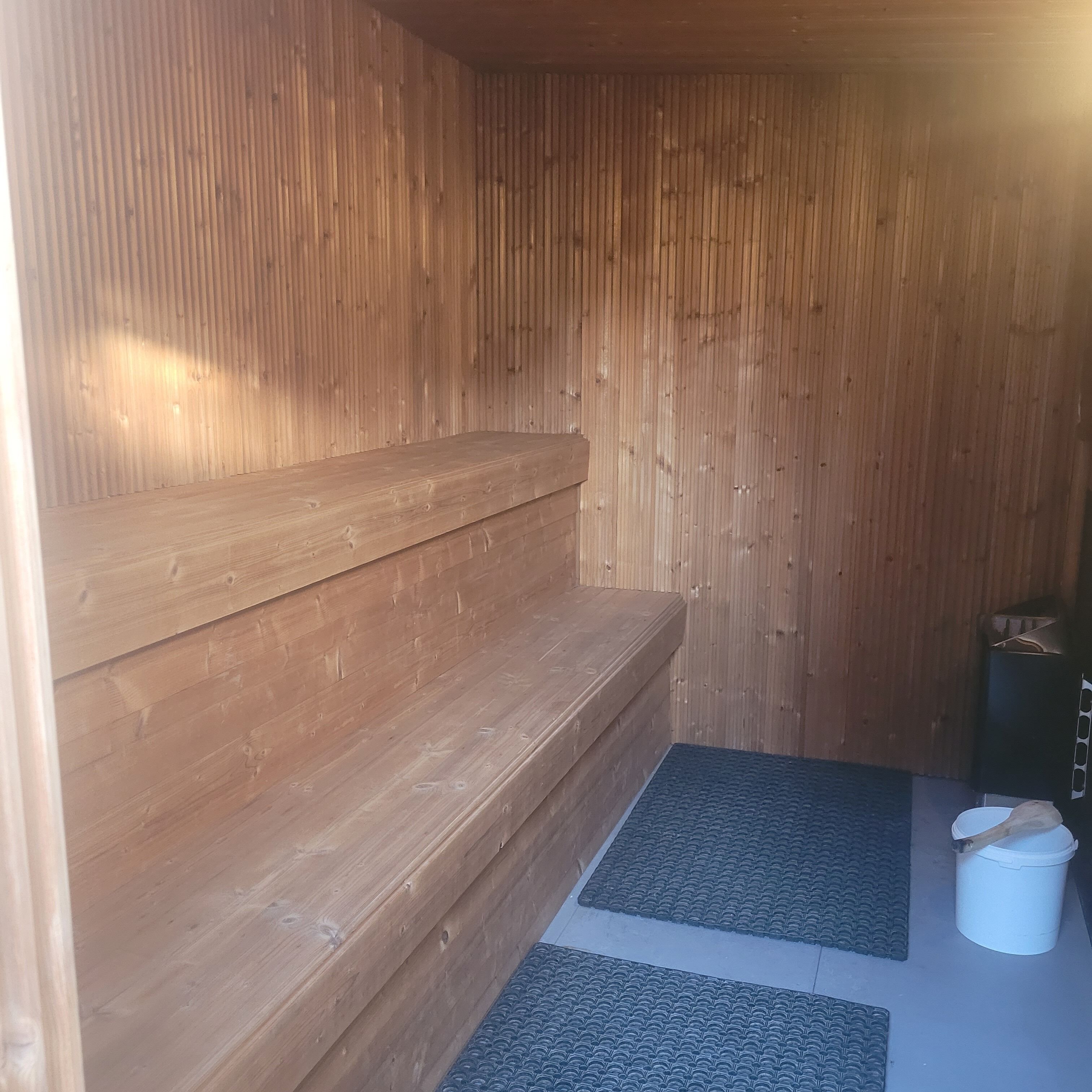 Una sala de sauna con bancos de madera y un tapete en el suelo.