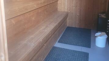 Una sala de sauna con bancos de madera y un tapete en el suelo.