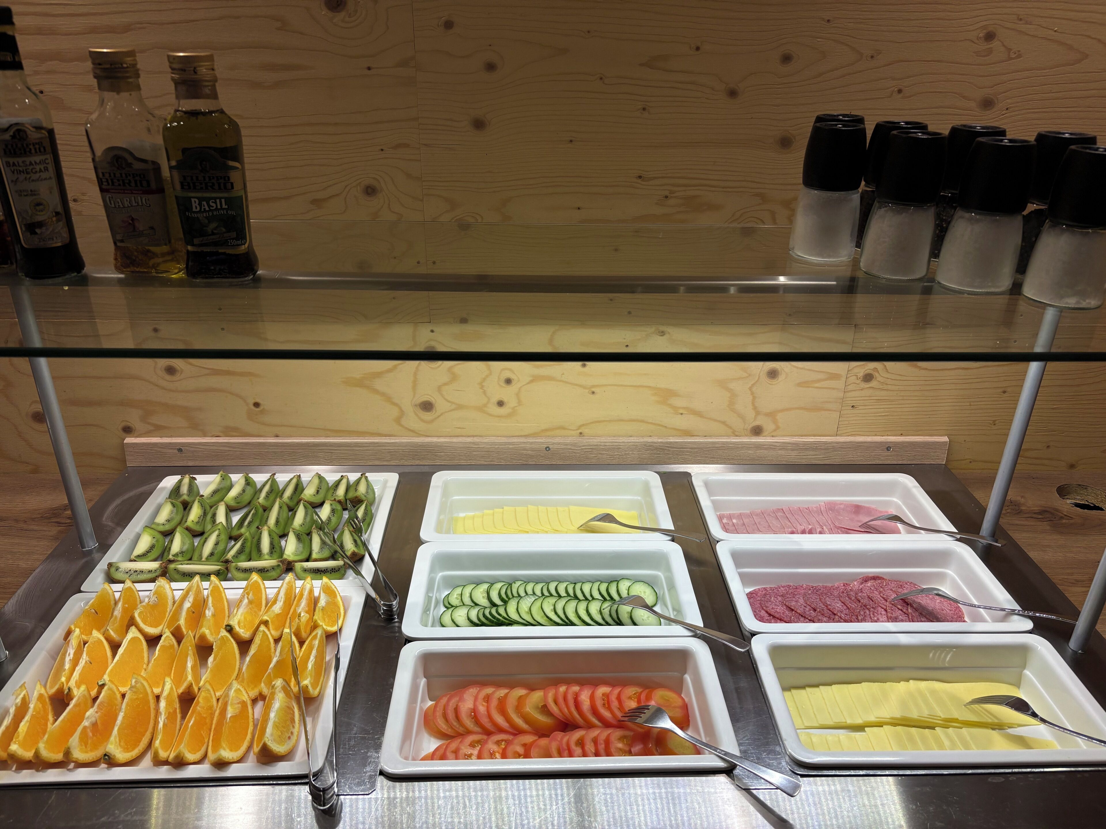 A buffet with various food items including fruits, vegetables, and condiments.