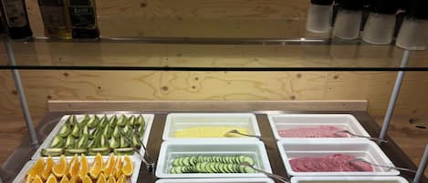 A buffet with various food items including fruits, vegetables, and condiments.