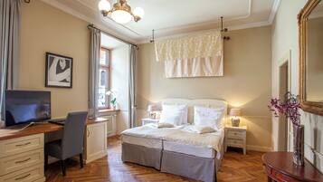 A bedroom with a bed, bedside tables, a desk with a chair, a television, and a window with curtains.