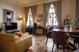 Una sala de estar con sofá, televisor, lámpara y comedor con sillas y mesa.