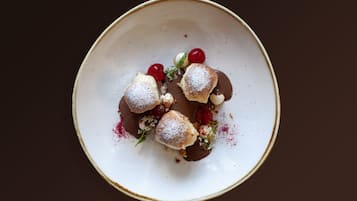 Une assiette à dessert avec trois pâtisseries, des cerises et du sucre glace.