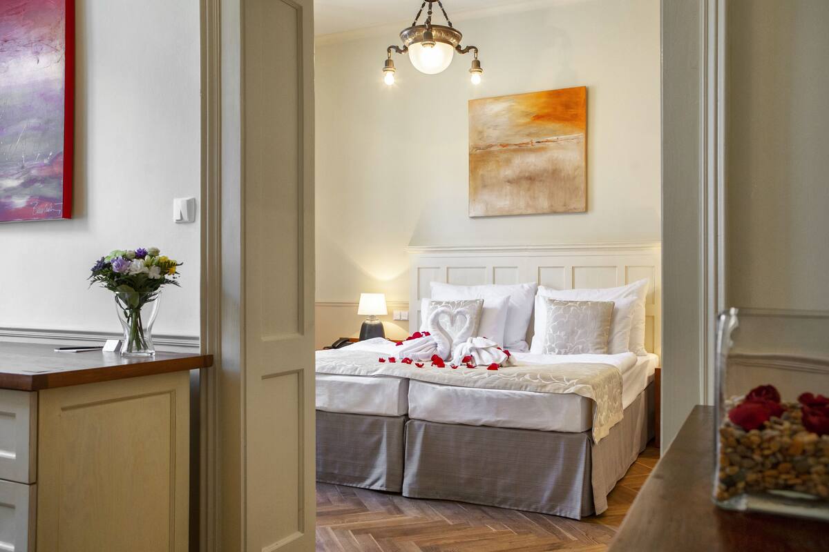 A bedroom with a bed, a nightstand, a lamp, and a painting on the wall.