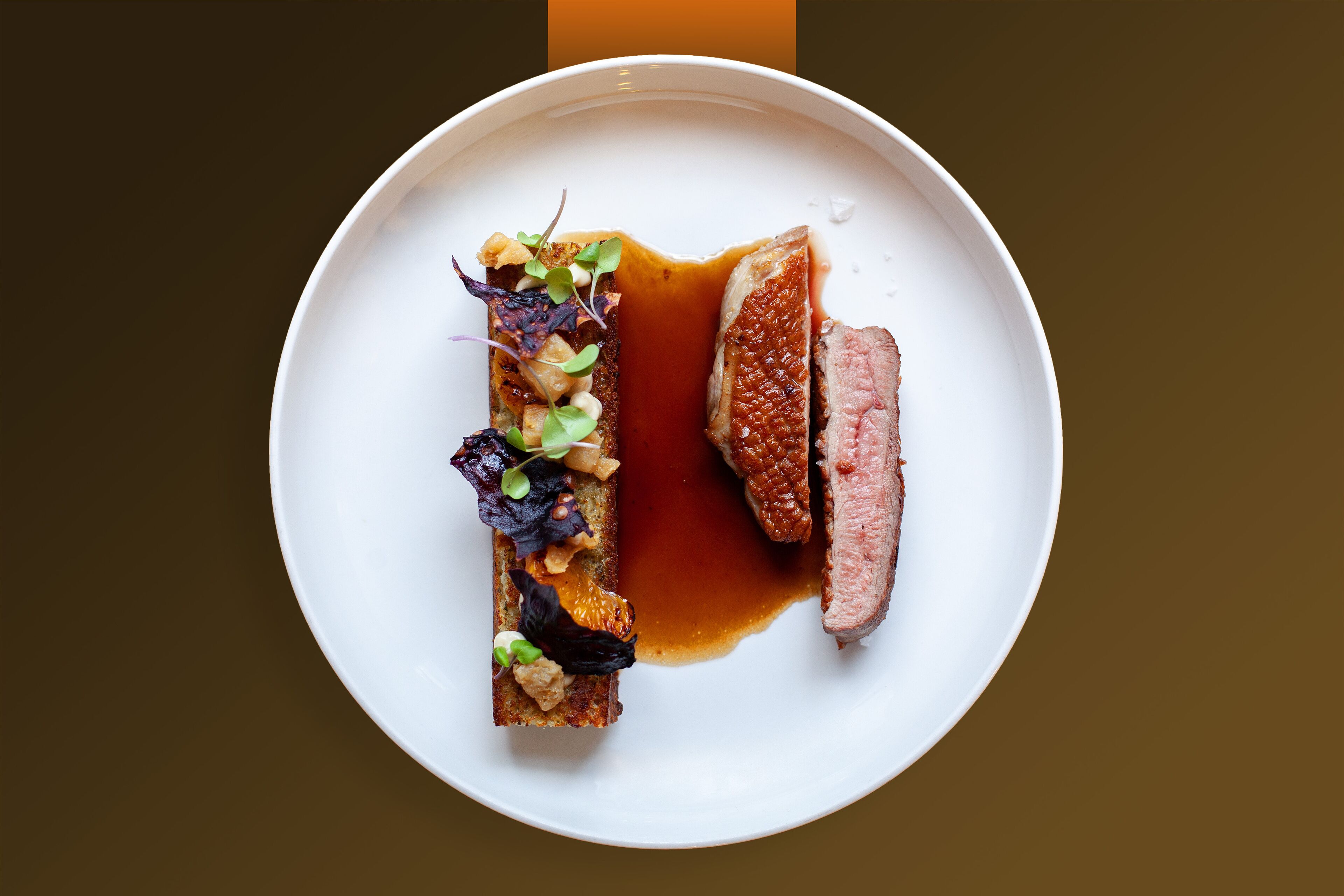 Un plato blanco con un trozo de carne y un recipiente pequeño con salsa.