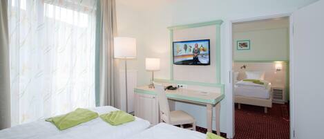 Une chambre d’hôtel avec deux lits, un bureau, une télévision et une chambre à coucher séparée.