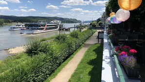 Un paseo fluvial con una barca amarrada en el agua, un letrero que dice 'DISCO SUNRISE' y asientos exteriores con flores.
