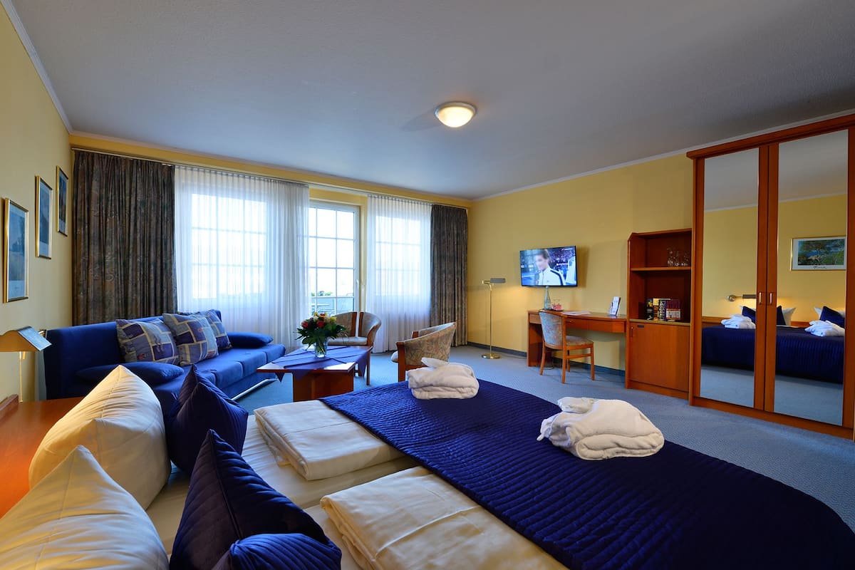 Ein Hotelzimmer mit Bett, Sofa, Schreibtisch und Fernseher.