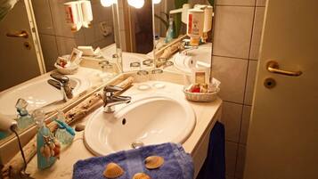 Un baño con dos lavamanos, un espejo y artículos de aseo.