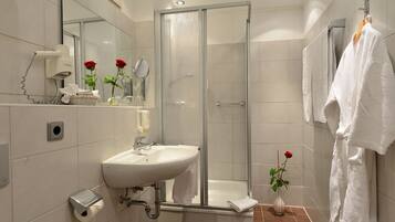 A modern bathroom with a glass shower enclosure, a white sink, and a mirror.