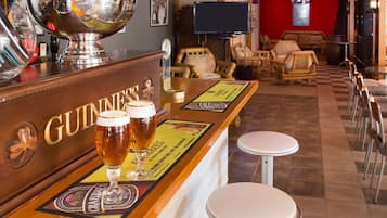 A bar area with Guinness branding, two glasses of beer, and a large silver bowl.