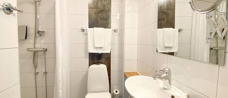 A modern bathroom with a shower, toilet, sink, and mirrors.