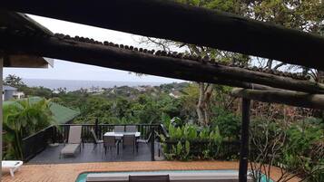 Uma área de piscina com pérgola, assentos externos e vista para o oceano.