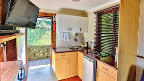 Cocina compacta con armarios de madera, un lavamanos y lavavajillas.