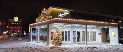 A hotel with a Christmas tree and lights, a sign for 'Monte Cristo Hotel & Suites', and a 'Prix Competitions' sign.