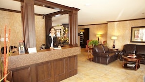 A reception area with a marble counter, leather seating, and a large mirror. - Hotel & Suites Monte-Cristo (L'Ancienne-Lorette)