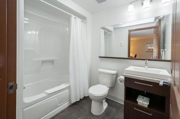 A modern bathroom with a bathtub, toilet, and vanity. - Hotel & Suites Monte-Cristo (L'Ancienne-Lorette)