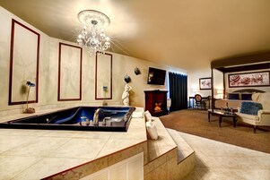 Amplia sala de estar con una bañera grande, chimenea y un espacio de descanso confortable.