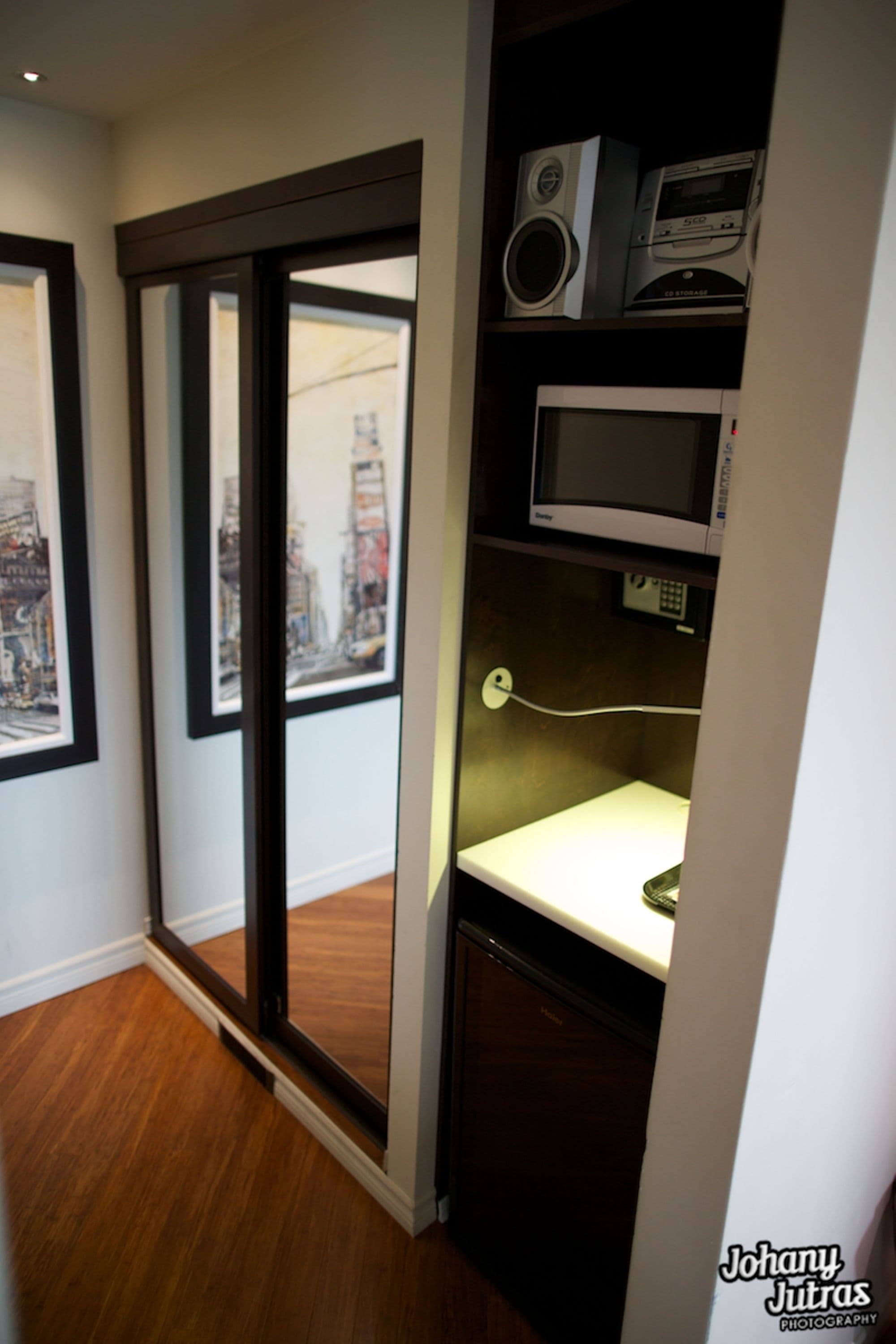 Quarto com porta de correr de vidro para vista da cidade, micro-ondas e pequena mesa com tomada.