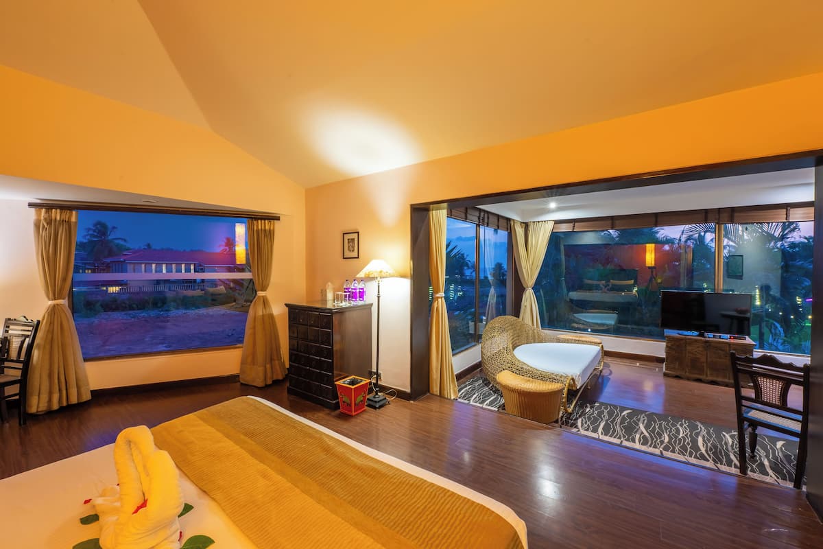 Habitación de hotel con una cama grande, un escritorio, una silla, un televisor y vistas al exterior.