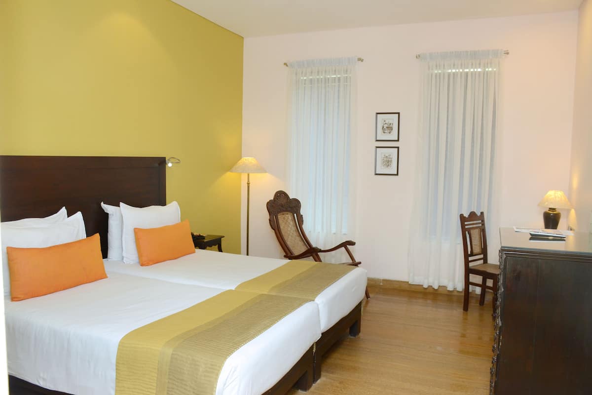 Una habitación de hotel con una cama grande, dos mesitas de noche, un escritorio y una silla.