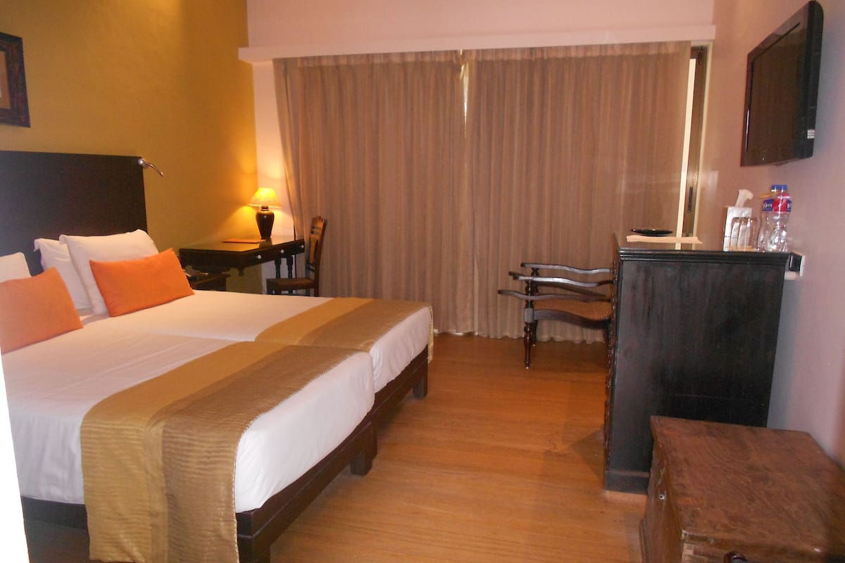 Habitación de hotel con una cama grande, un escritorio, una silla y un televisor en la pared.