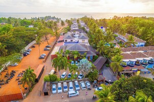 A coastal hotel with multiple-story buildings, a parking area, and a beach view.
