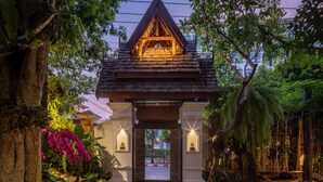 A traditional wooden structure with a peaked roof, surrounded by lush greenery and flowering plants. - Khum Phaya Resort & Spa Boutique Collection (Chiang Mai)