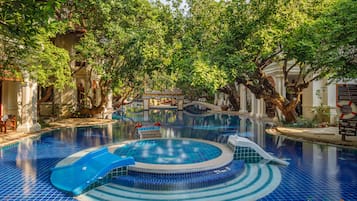 A pool area with a hot tub, lounge chairs, and a slide.
